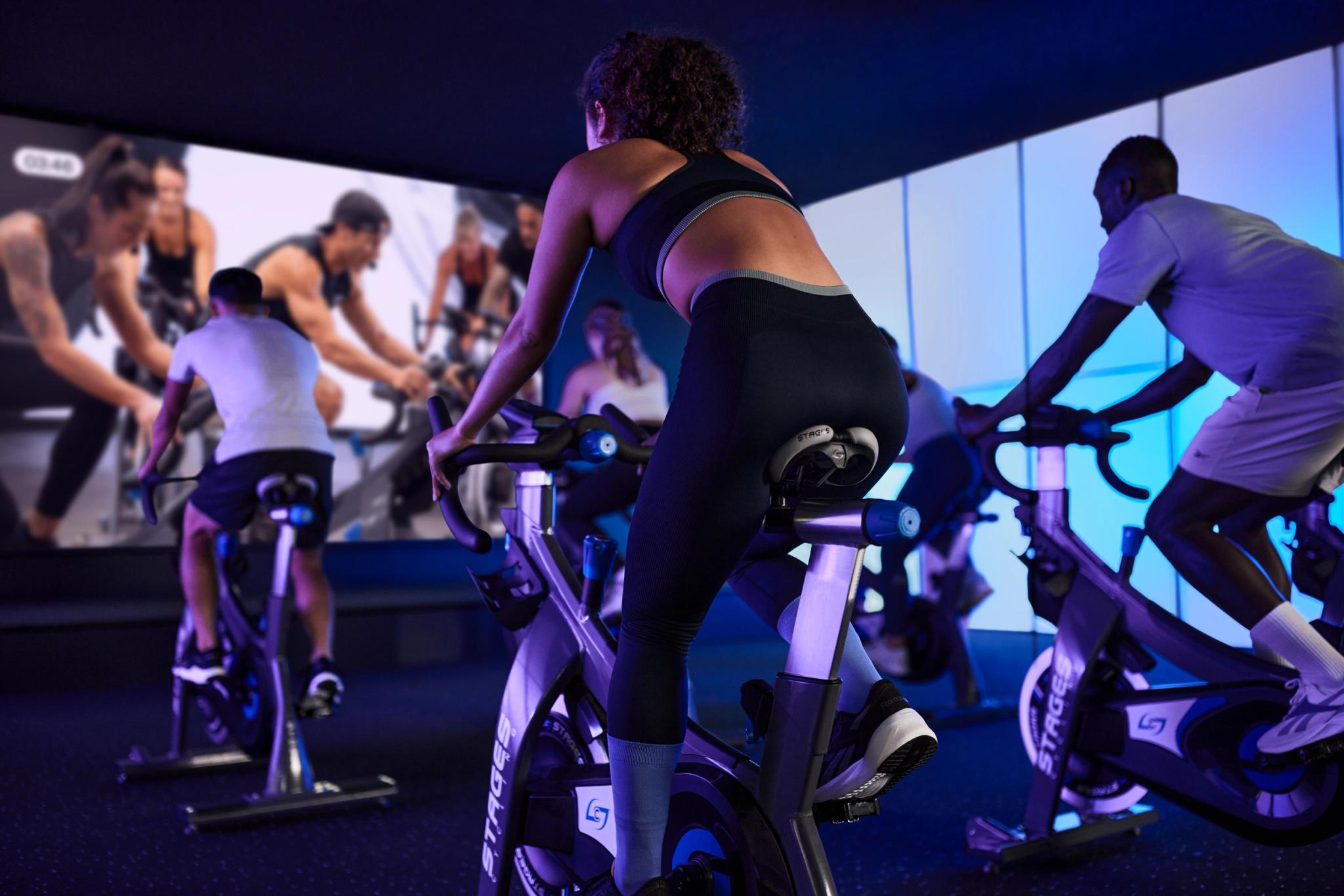 Cours de vélo indoor dynamique à Webody Saint-Orens avec écrans géants et ambiance lumineuse bleue